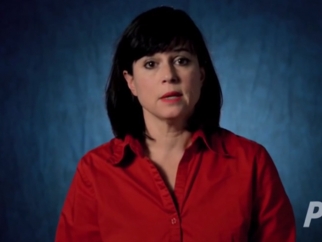 A woman in a red shirt is standing in front of a blue background.