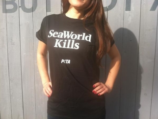 A woman wearing a black t -shirt that says seaworld kills.