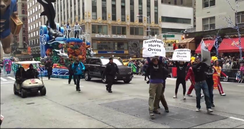 A group of people walking down a street in a city.