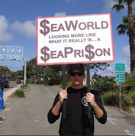 A man holding up a sign that says seaworld.