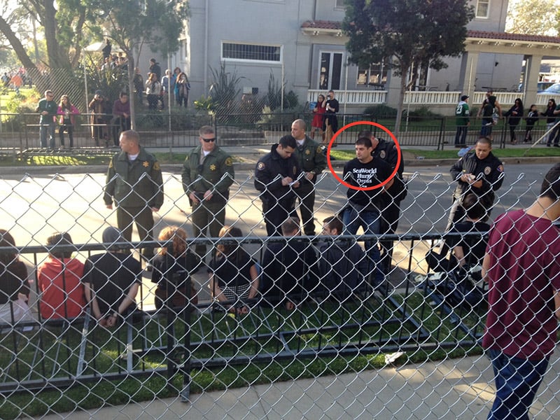 A group of people standing behind a chain link fence.