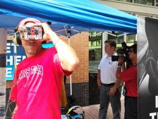A man in a pink shirt is holding a virtual reality headset.