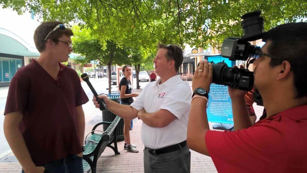 A man in a red shirt is being interviewed by a cameraman.