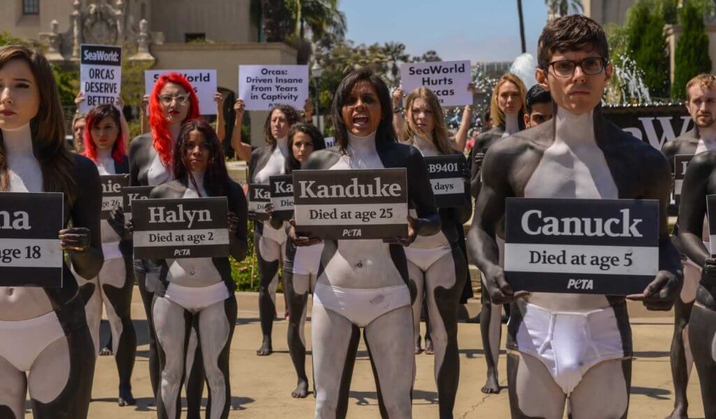 A group of people dressed in body suits holding signs.