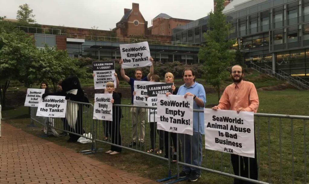 A group of people holding signs in front of a fence.