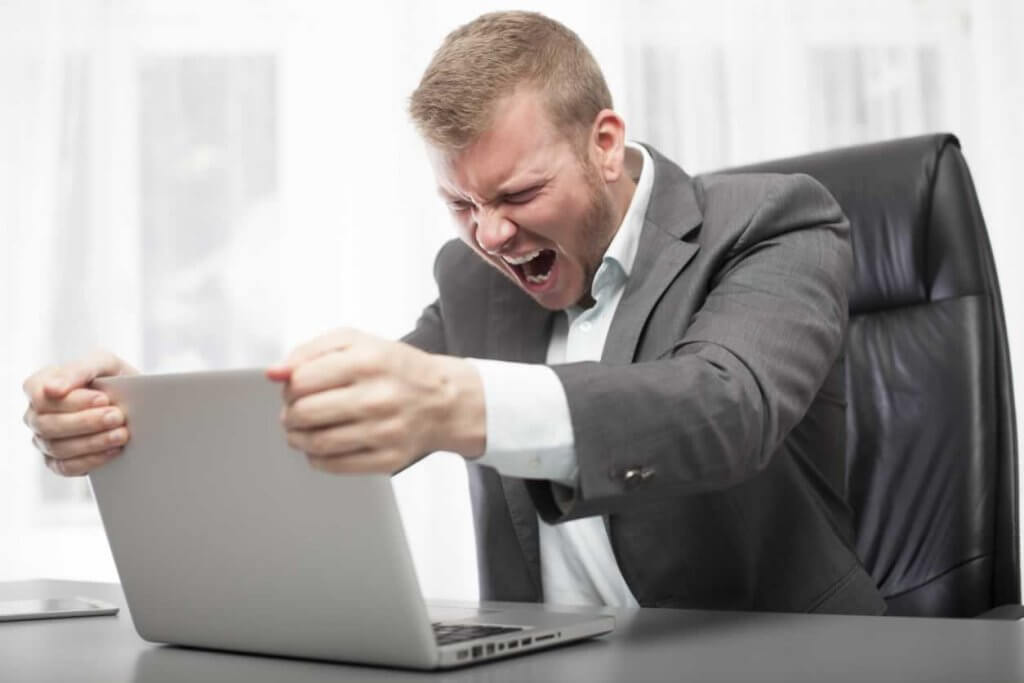 A businessman angrily shouting at his laptop in the office while analyzing Seaworld revenue.