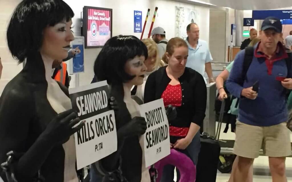 A group of people holding signs in an airport.