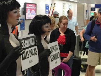A group of people holding anti-SeaWorld signs in an airport.