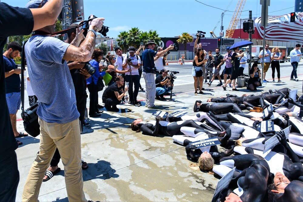 A group of people laying on the ground in front of a camera.