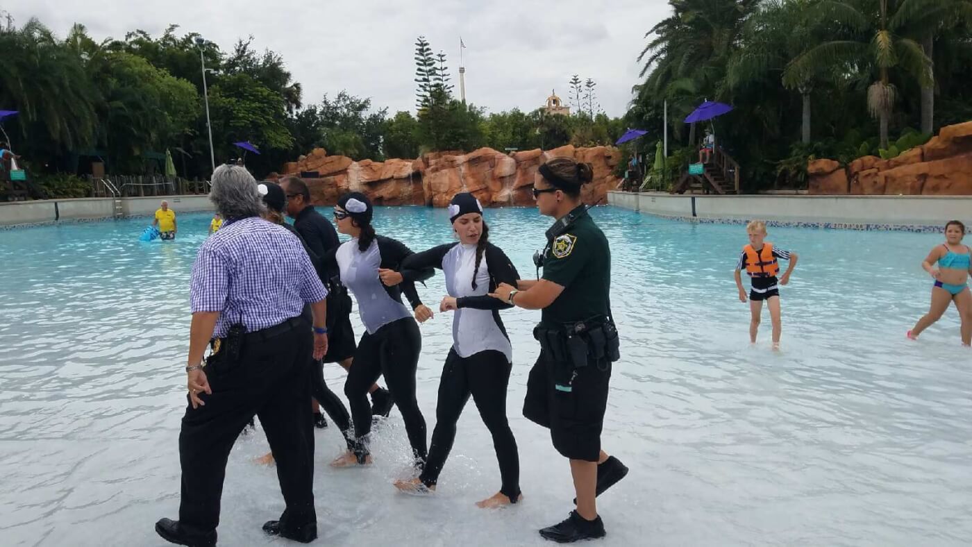 A group of people standing in a pool with a police officer.