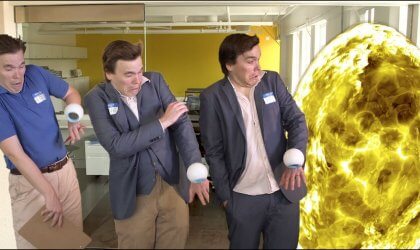 A group of men standing next to a large yellow ball.