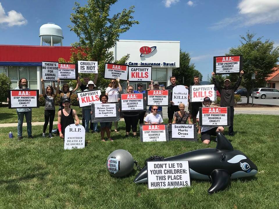 A group of people holding AAA signs in front of a store.