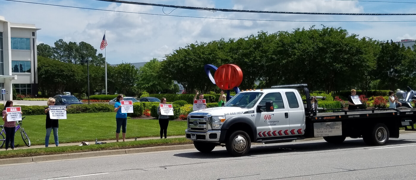 A group of people holding AAA signs on a truck in front of a building.