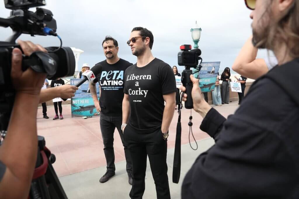 Two men in black t-shirts, including Christopher Von Uckermann, standing in front of a camera.